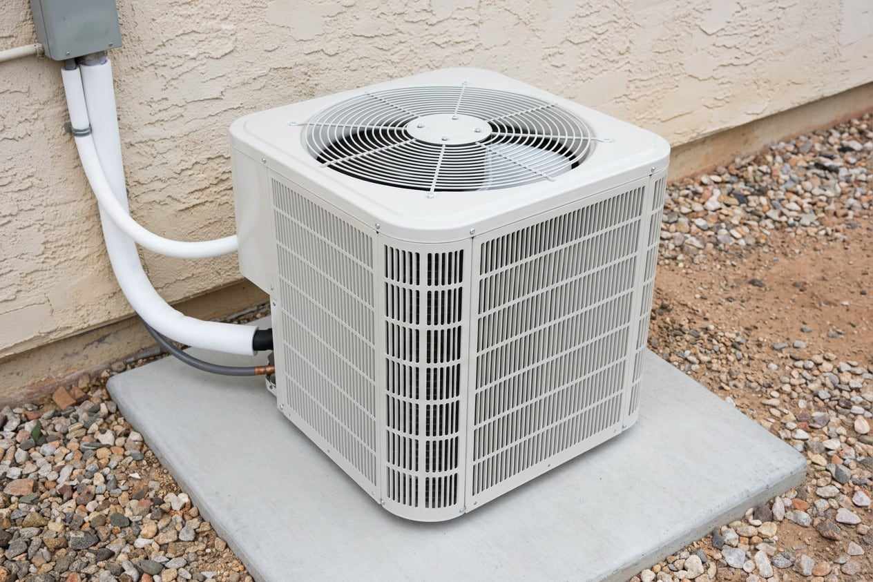 A new white AC unit on a clean pad with new line insulation and raked gravel